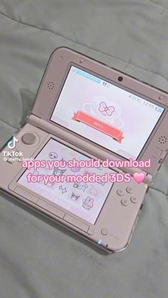 an open nintendo wii game system sitting on top of a bed with the caption saying, apps you should downloaded for your moded 3ds