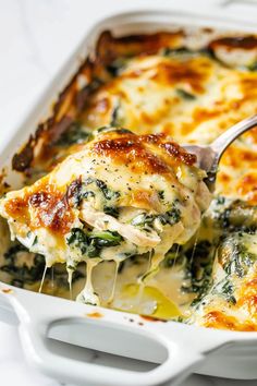 a casserole dish with spinach and cheese being lifted from the casserole