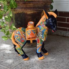 a ceramic figurine of a horse on the ground next to a potted plant