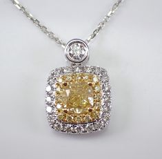 18K White Gold Cushion-cut Yellow Canary Diamond Pendant with Chain. This pendant is set with a natural Cushion cut Brilliant center Diamond. This Diamond is a fancy yellow canary color and weighs 1.01 carat. There are also sixteen natural Fancy Yellow Canary Round Diamonds and twenty-three round Brilliant white/colorless Diamonds set in this pendant. These diamonds are G/H color (white), SI clarity and weigh a total of .54 carat.  The total diamond weight of this necklace is 1.55 carats.  This Yellow Diamond Pendant, Canary Color, Canary Yellow Diamonds, Yellow Canary, Canary Diamond, Halo Necklace, Colorless Diamond, White Gold Chains, Canary Yellow