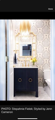 a bathroom with a mirror, sink and toilet next to a blue curtained door