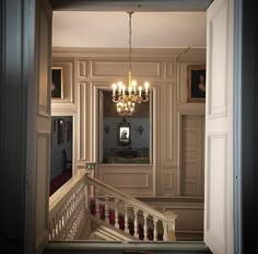 an open door leading to a hallway with chandelier