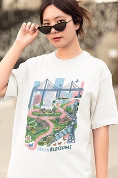 Embrace the fusion of cityscapes and nature with our Urban Blossoms Oversize T-Shirt. Featuring a vibrant graphic print that combines iconic urban architecture with a lush, winding garden, this tee captures the harmony of metropolitan life and the beauty of green spaces. The design is complemented by delicate butterflies and flowers, adding a whimsical touch. Made from soft, breathable fabric, this oversized fit offers maximum comfort and effortless style, perfect for a casual day out or a relaxed weekend look. Comfort and style is the name of the game for these custom boxy t-shirts. Their relaxed fit along with the dropped shoulders add that modern aesthetic that can blend into any occasion. All shirts are made with 100% airlume, ring-spun and combed cotton for extra softness. (Athletic H Dreaming Art, Art Tshirt, Butterflies And Flowers, Urban Architecture, Oversize T Shirt, Tshirt Art, Vintage Graphic, Modern Aesthetic, Vintage Graphics