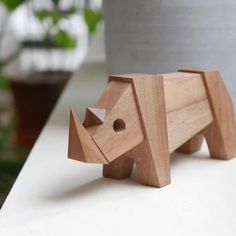 a wooden elephant figurine sitting on top of a table next to a potted plant