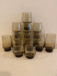 a stack of glasses sitting on top of a table next to each other in front of a white wall