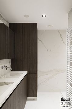 a bathroom with marble counter tops and white tile flooring, along with dark wood cabinetry