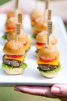 mini hamburgers with toothpicks in the middle on a white plate