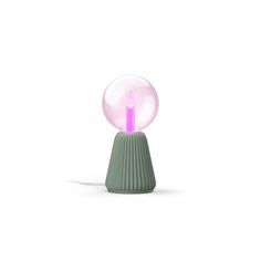 a pink light sitting on top of a green vase next to a white wall and floor