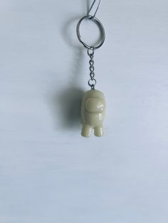 an elephant shaped keychain hanging from a metal hook on a white surface,