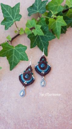 the earrings are made with blue seed beads and beadwork, which is hanging from a tree branch