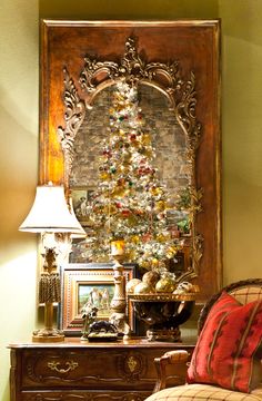 a living room with a christmas tree on the wall next to a chair and lamp