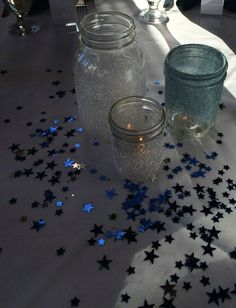 three jars are sitting on a table with blue and silver confetti