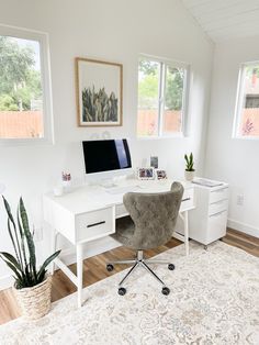 a white desk with a computer on top of it next to a potted plant