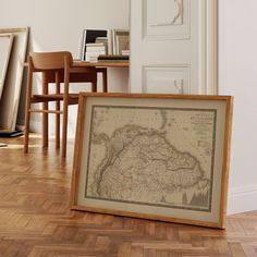 a framed map sitting on top of a hard wood floor next to a wooden table