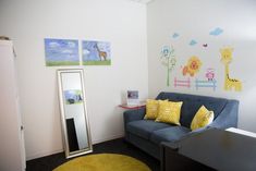 a living room with a blue couch, mirror and wall decals on the walls