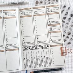 an open planner with stickers and pens on it next to a pen, ruler and marker