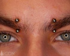 a man's eyes with piercings on their forehead and eyebrows are seen in this close up photo