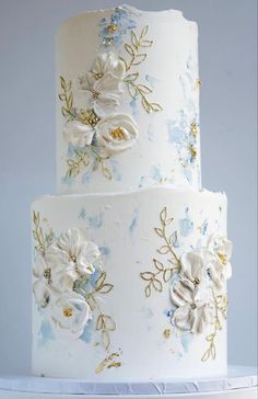 a three tiered cake with white and blue flowers on it