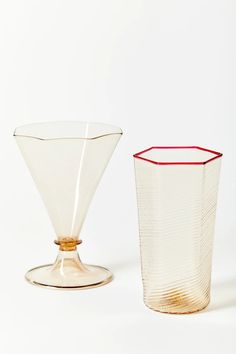 two glass vases sitting next to each other on a white surface with red trim