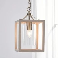 a light fixture hanging from the ceiling in front of a white wall with a window