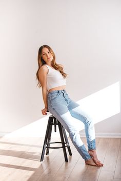 a beautiful young woman sitting on top of a stool