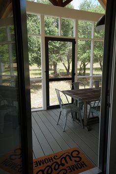 a table and chairs on a porch with an open door leading to the back yard