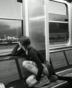 a woman sitting on a train seat with her head in her hands while looking out the window