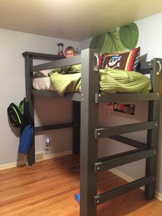 there is a bunk bed in the corner of this room with a little boy sitting on it