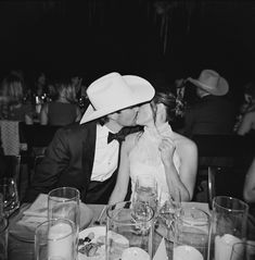 a man and woman kissing at a dinner table