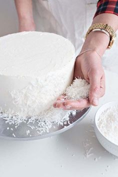 a person is decorating a cake with white frosting