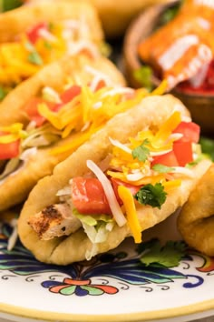 three tacos on a colorful plate with condiments