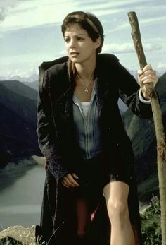 a woman holding a stick on top of a mountain