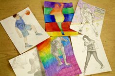 four different colored paper pictures on a table with pencils and crayon markers