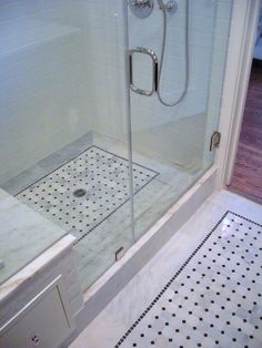 a walk in shower sitting next to a white sink and tiled floor with black dots on it