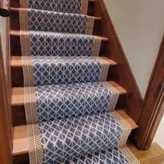 a set of stairs with blue and white rugs on the bottom, next to a wooden handrail