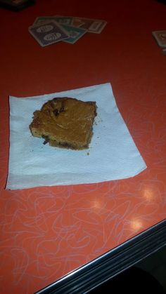 a piece of cake sitting on top of a white paper towel in front of a red table