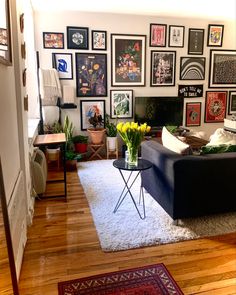 a living room filled with furniture and lots of framed pictures on the wall above it