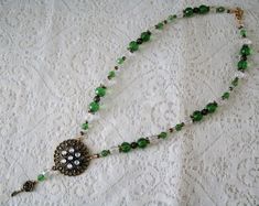 "This beautiful necklace has green faceted beads, clear faceted beads, seed beads, gold plated filigree beads, brass accent beads, a brass filigree pendant with rhinestone accents and brass key charm. 18\" long. Toggle clasp." Ornate Round Beads For Jewelry Making, Elegant Green Necklace With Bead Caps, Antique Beaded Jewelry With Czech Glass, Vintage Wire Wrapped Round Bead Jewelry, Victorian Beaded Jewelry Gift, Green Round Beaded Jewelry With Bead Caps, Victorian Beaded Jewelry For Gifts, Elegant Bronze Jewelry With Faceted Beads, Victorian Handmade Necklaces With Round Beads