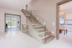 a staircase with glass railing and wooden handrails in a modern style home setting