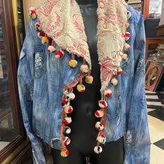 a mannequin wearing a denim jacket with pom - poms on it