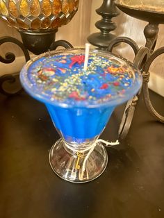 a blue drink sitting on top of a table next to a vase with a candle in it