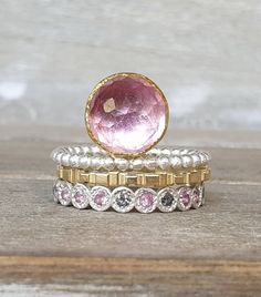 A gorgeous set of rings, you can buy them separate or as a set. We have a central ring with a pink topaz wrapped in a 22k bezel set aside with my silver dot band. Then my cube 14k gold band and my silver half infinity diamond and pink sapphire band. The combo is so unique, you can play with those rings so much. A pastel set to feel unique. Made to order, size 7, can be resized. Pink Sapphire Band, Pink Topaz Ring, 22k Gold Ring, Gemstone Stacking Ring, Multi Gemstone Ring, Tanzanite Jewelry, Sparkly Ring, Rose Gold Bangle, Sapphire Band