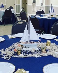 a sailboat is sitting on top of a table with plates and napkins around it