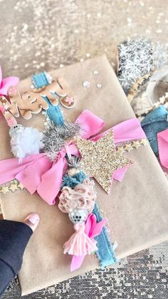 a gift wrapped in brown paper with pink bows and glitters on it next to other gifts