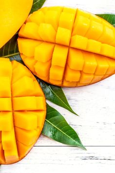 two pieces of mango sitting next to each other on top of a white wooden table