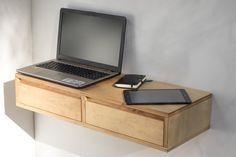 an open laptop computer sitting on top of a wooden desk next to a cell phone