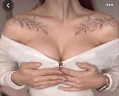 a woman with tattoos on her chest holding her hands in front of her chest and looking down at the camera