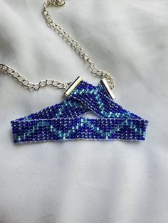 a blue beaded triangle necklace on a silver chain with a matching pendant attached to it