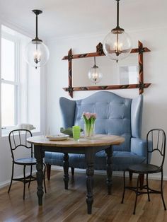 a blue chair and table in a room with wood flooring, white walls and windows