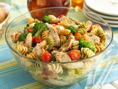 a glass bowl filled with pasta salad on top of a blue and white table cloth